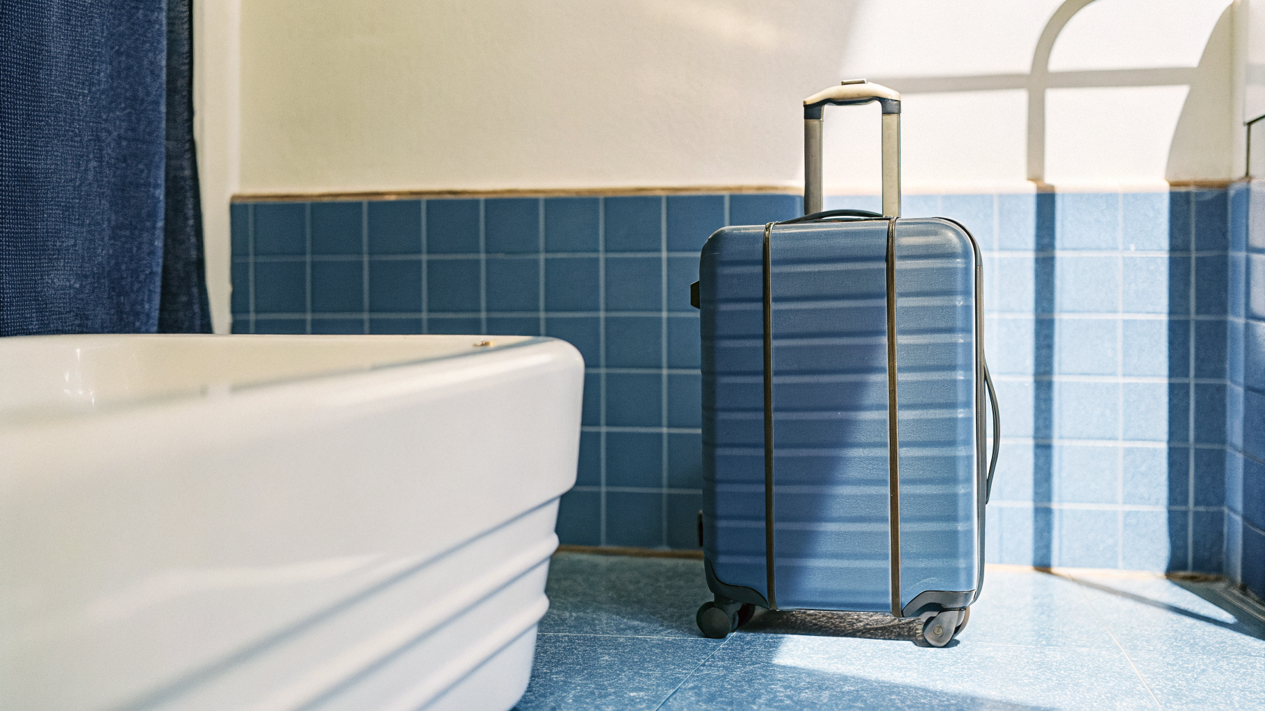 Valise posée dans la baignoire d'une salle de bain d'hôtel pour éviter le contact avec le lit